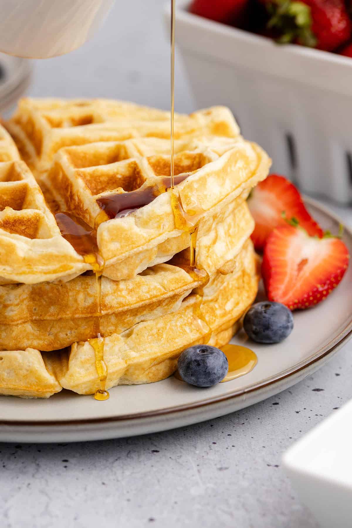 Gluten Free Buttermilk Waffles Stacked on a Plate with Syrup Pouring