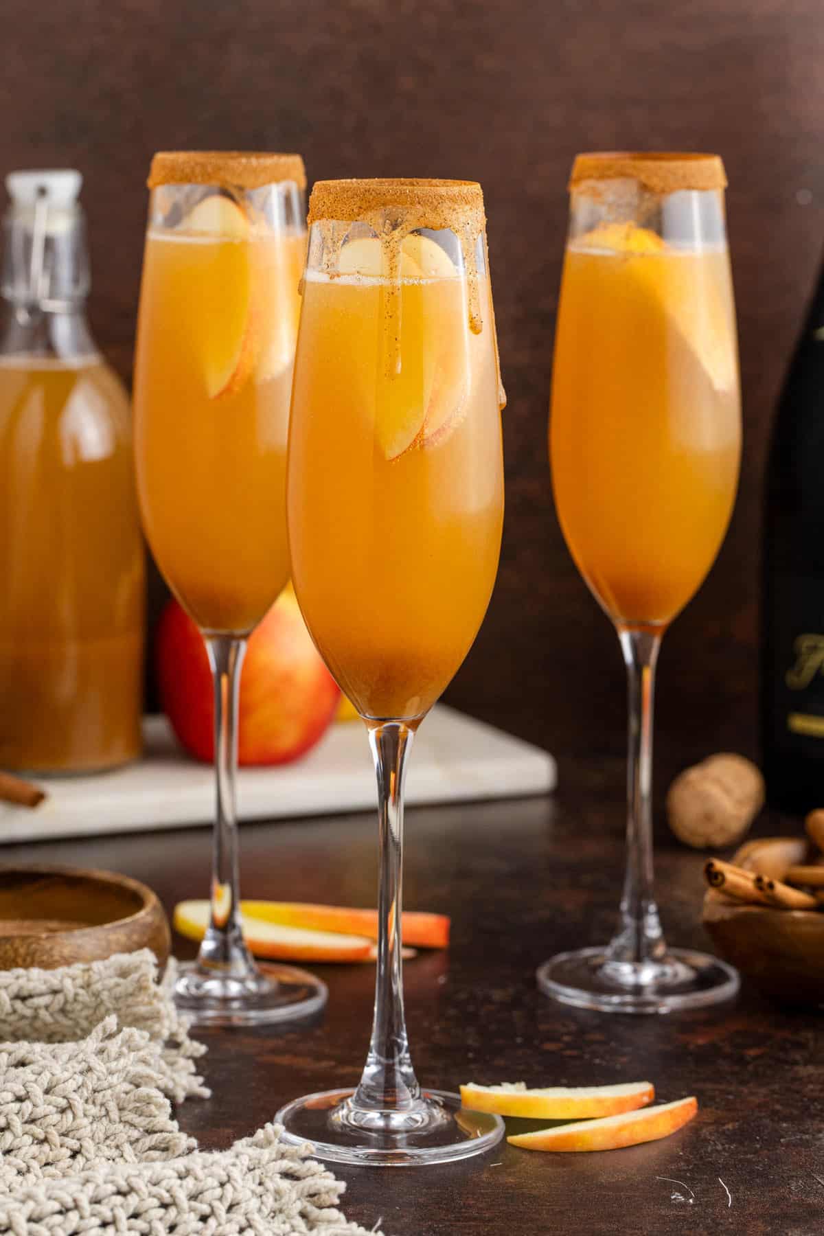 Apple Cider Mimosa in Champagne Flutes with Apple in Back