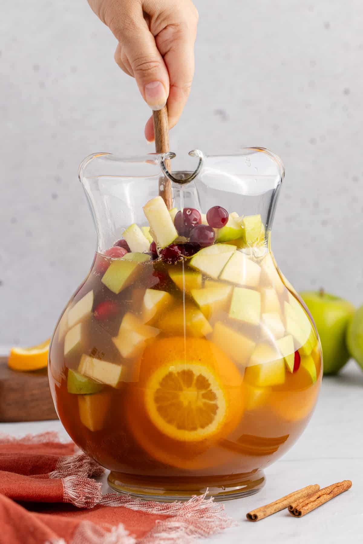 Apple Cider Sangria with White Wine in a Pitcher Being Mixed Together