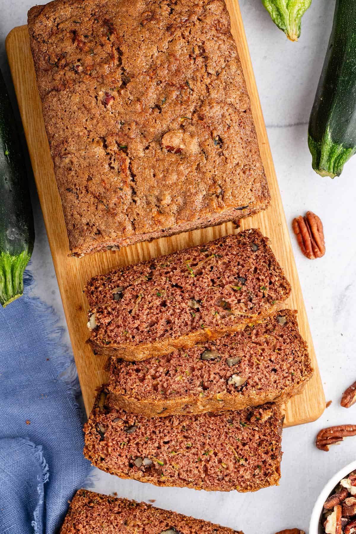 Gluten Free Zucchini Bread on a Cutting Board with Zucchini in Back