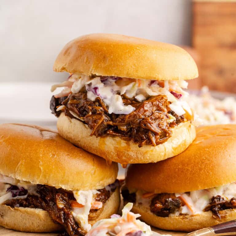BBQ pulled pork sliders with coleslaw stacked on a cutting board Close up