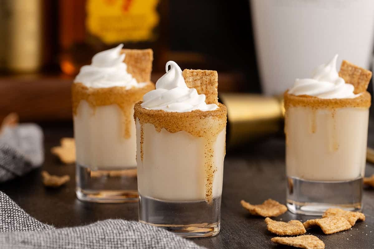 Cinnamon Toast Crunch Shots on a counter with Fireball and RumChata in the back