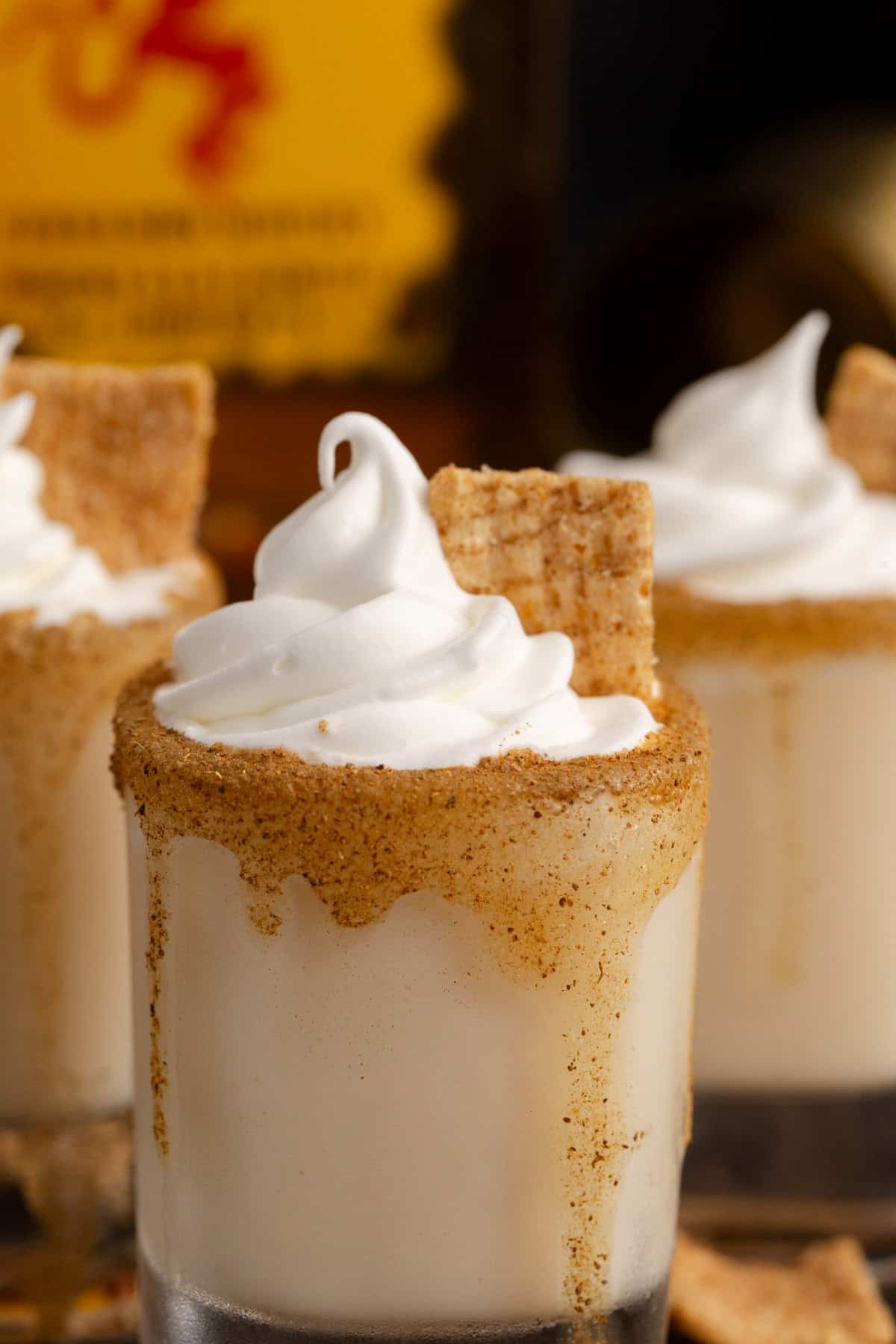 Cinnamon Toast Crunch Shots garnished with whipped cream up close