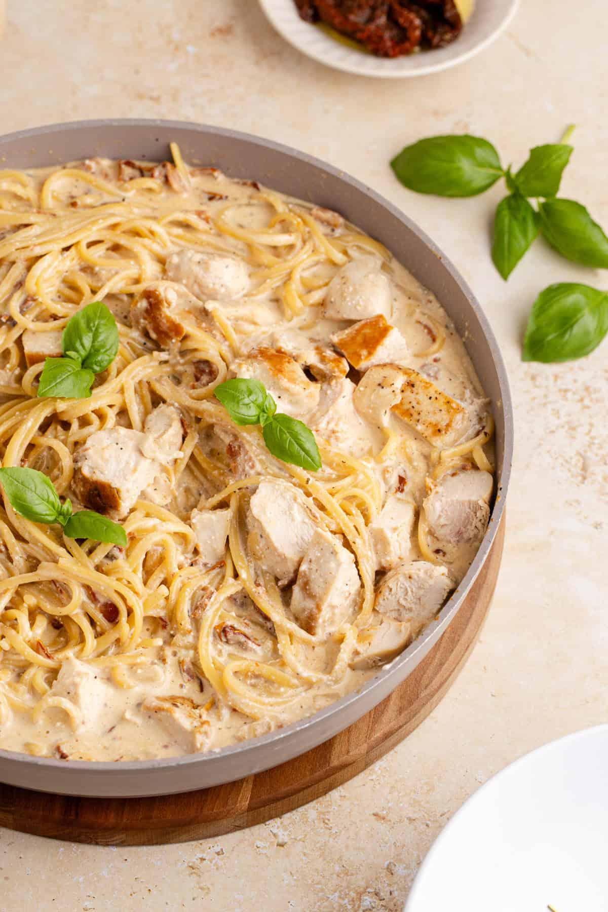Creamy Sun Dried Tomato Chicken Pasta made in a pan with basil garnish