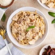 Creamy Sun Dried Tomato Chicken Pasta plated with fresh basil