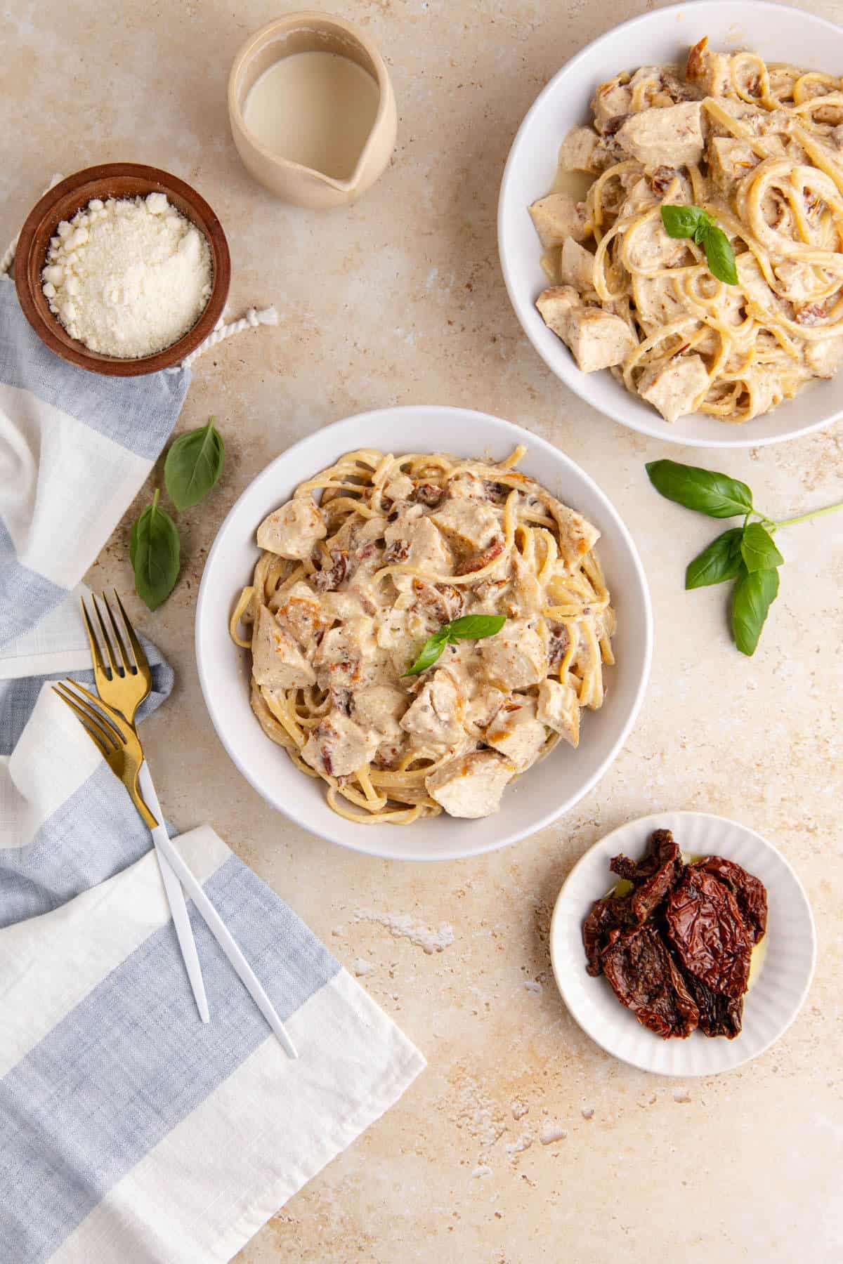 Creamy Sun Dried Tomato Chicken Pasta two bowls with fresh basil