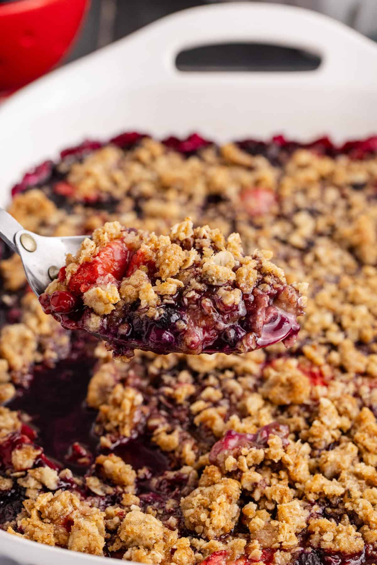 Mixed Berry Crisp with Frozen Berries baked with a scoop being taken out