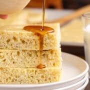 Sheet Pan Banana Pancakes stacked with syrup being poured