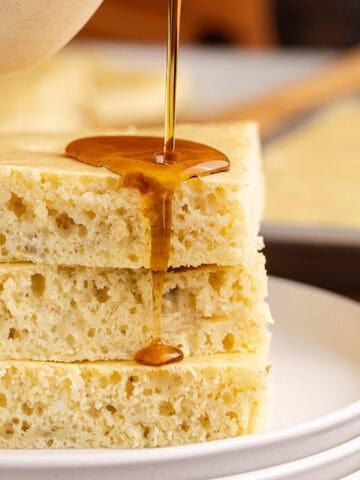 Sheet Pan Banana Pancakes stacked with syrup being poured
