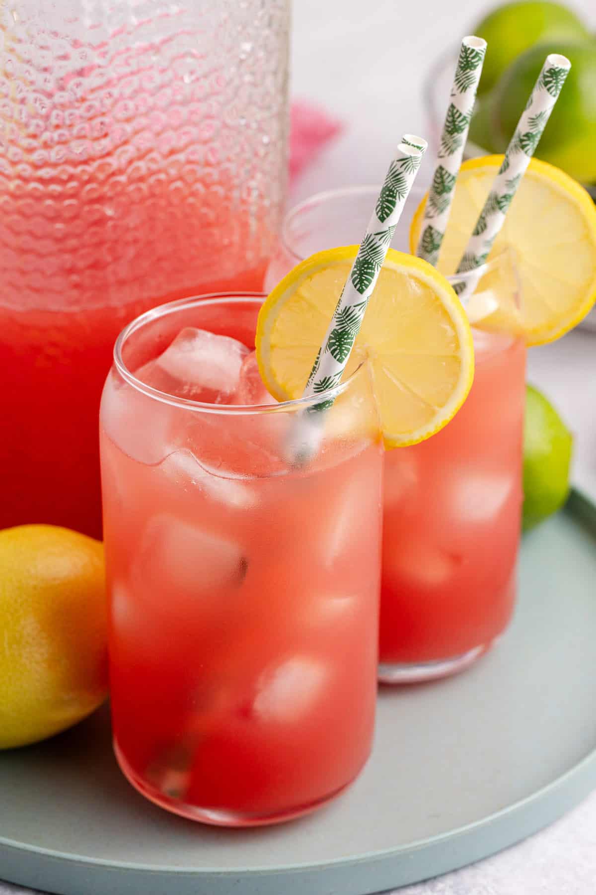 Watermelon Juice Served in Glass Over Ice with Lemon Slice on Tray with Pitcher