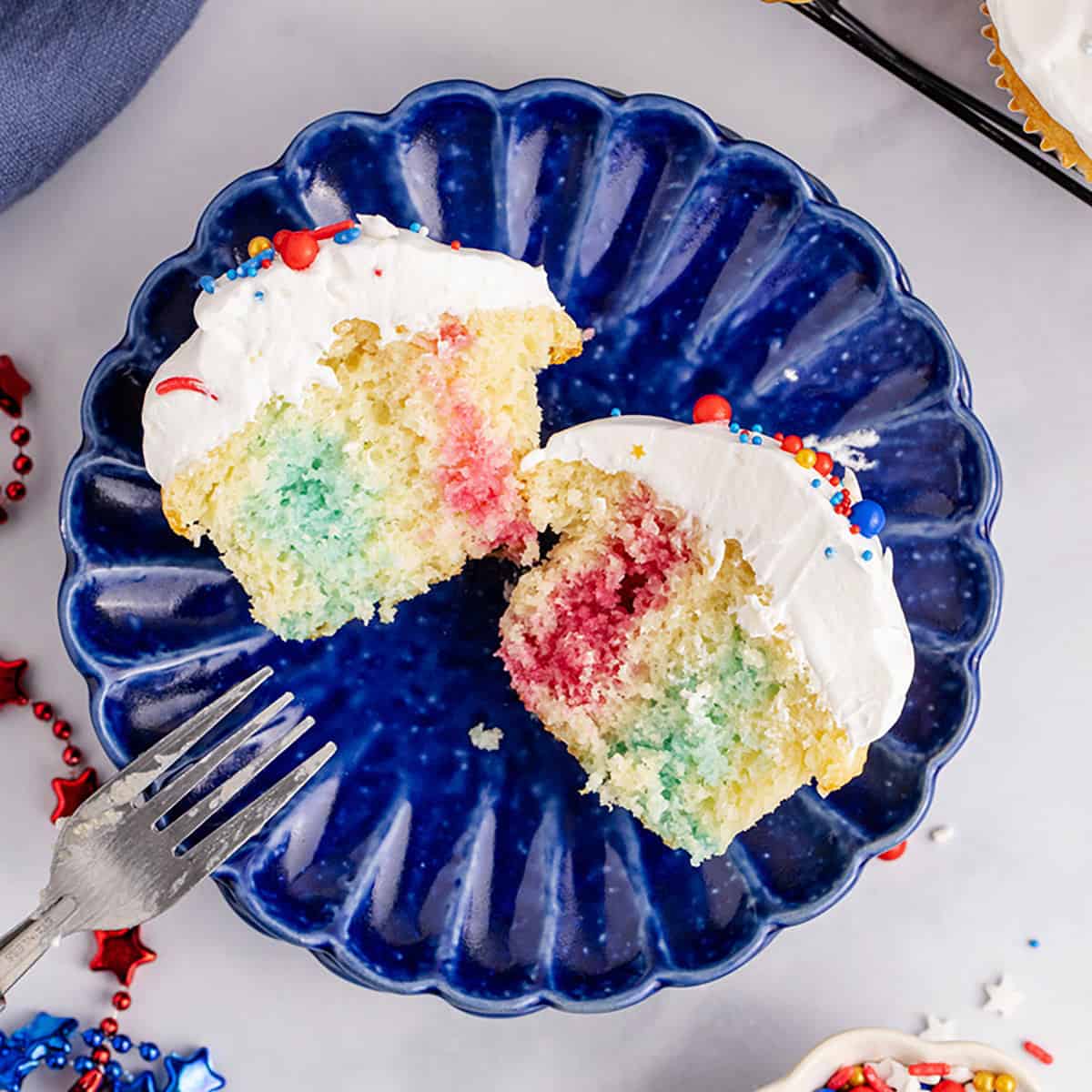 Red, White and Blue Cupcakes cut in half on a plate to show Jello colors inside