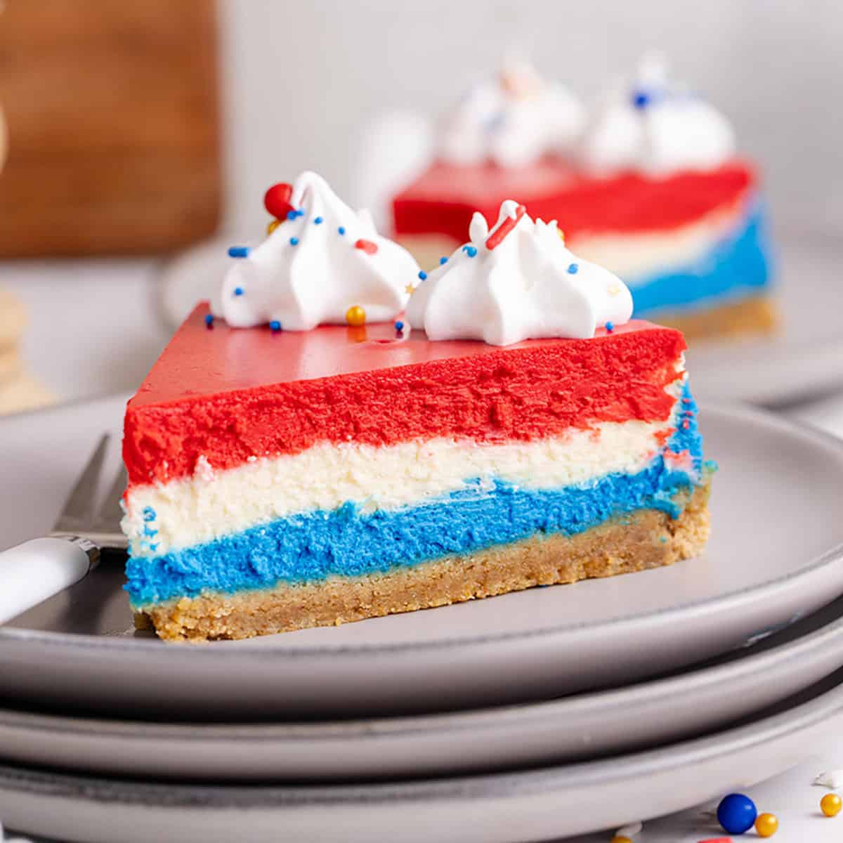 Red, White and Blue Layered Cheesecake on a plate with whipped cream close up