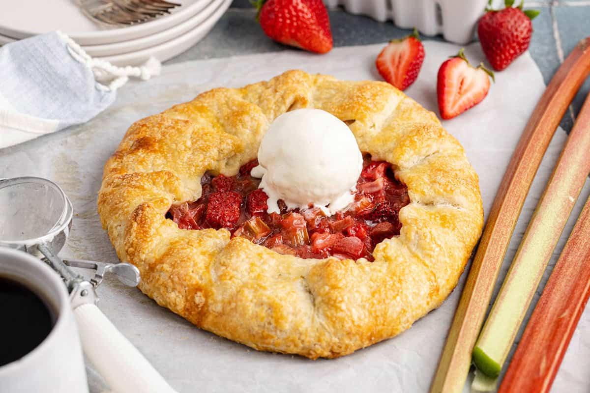 Strawberry Rhubarb Galette on parchment, scoop of ice cream on top