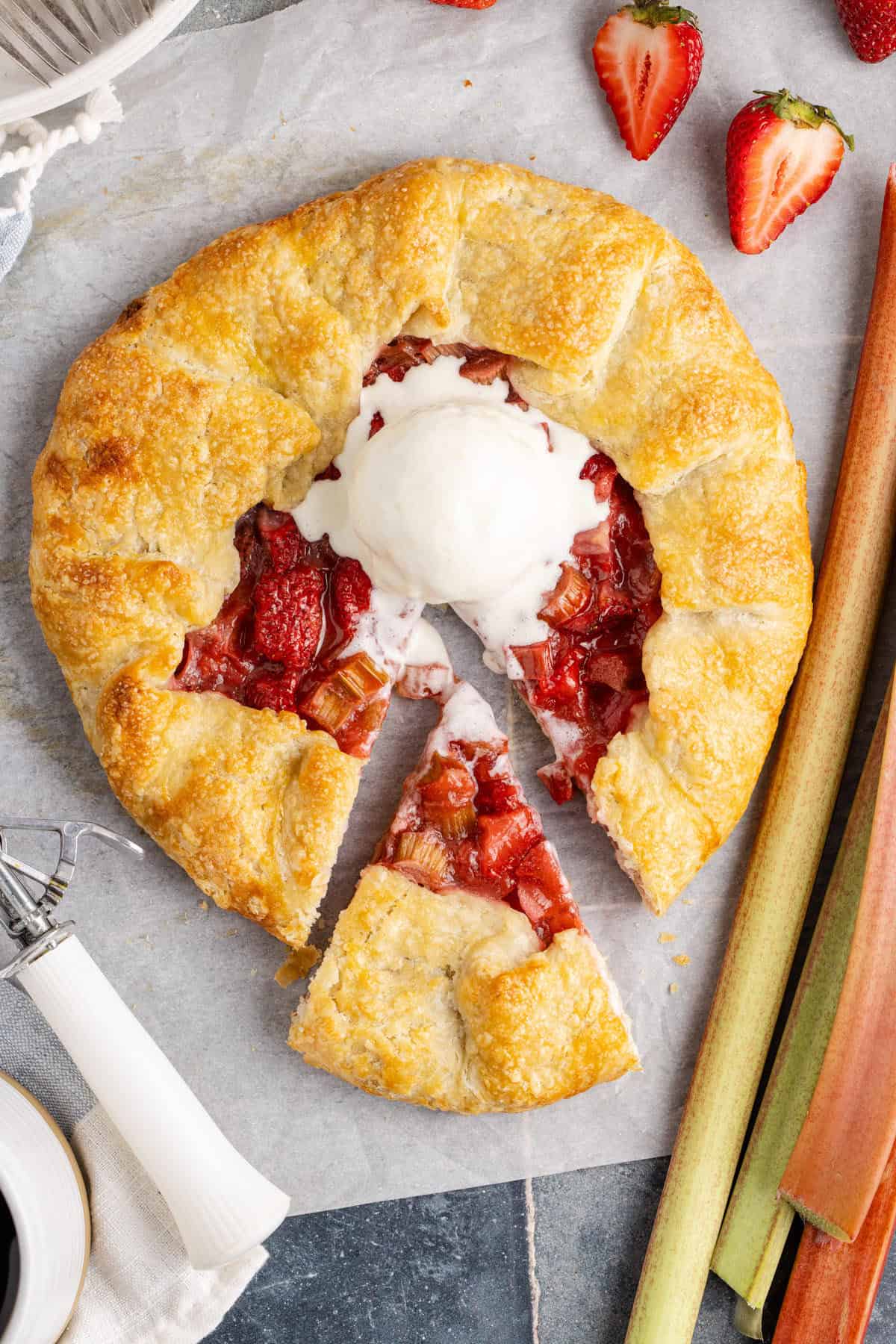 Strawberry Rhubarb Galette baked with a slice taken and ice cream on top