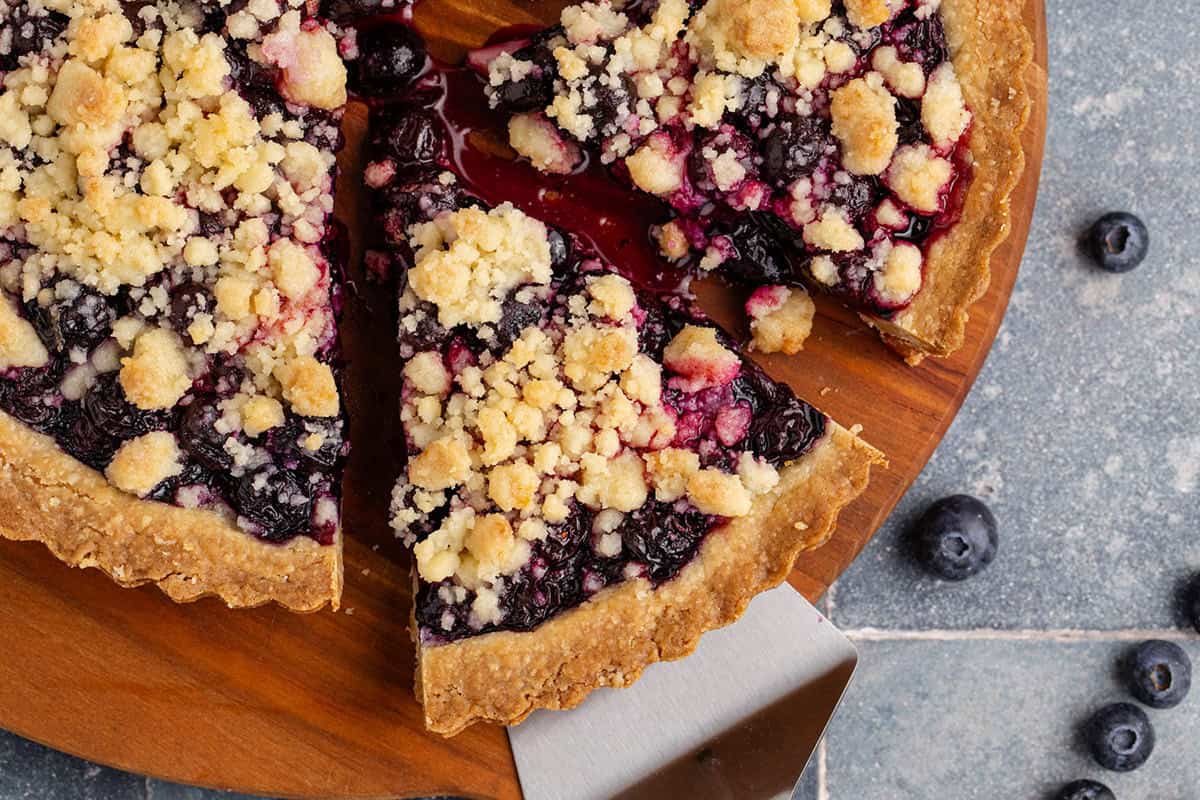 Blueberry Tart slices cut and one being taken with a server