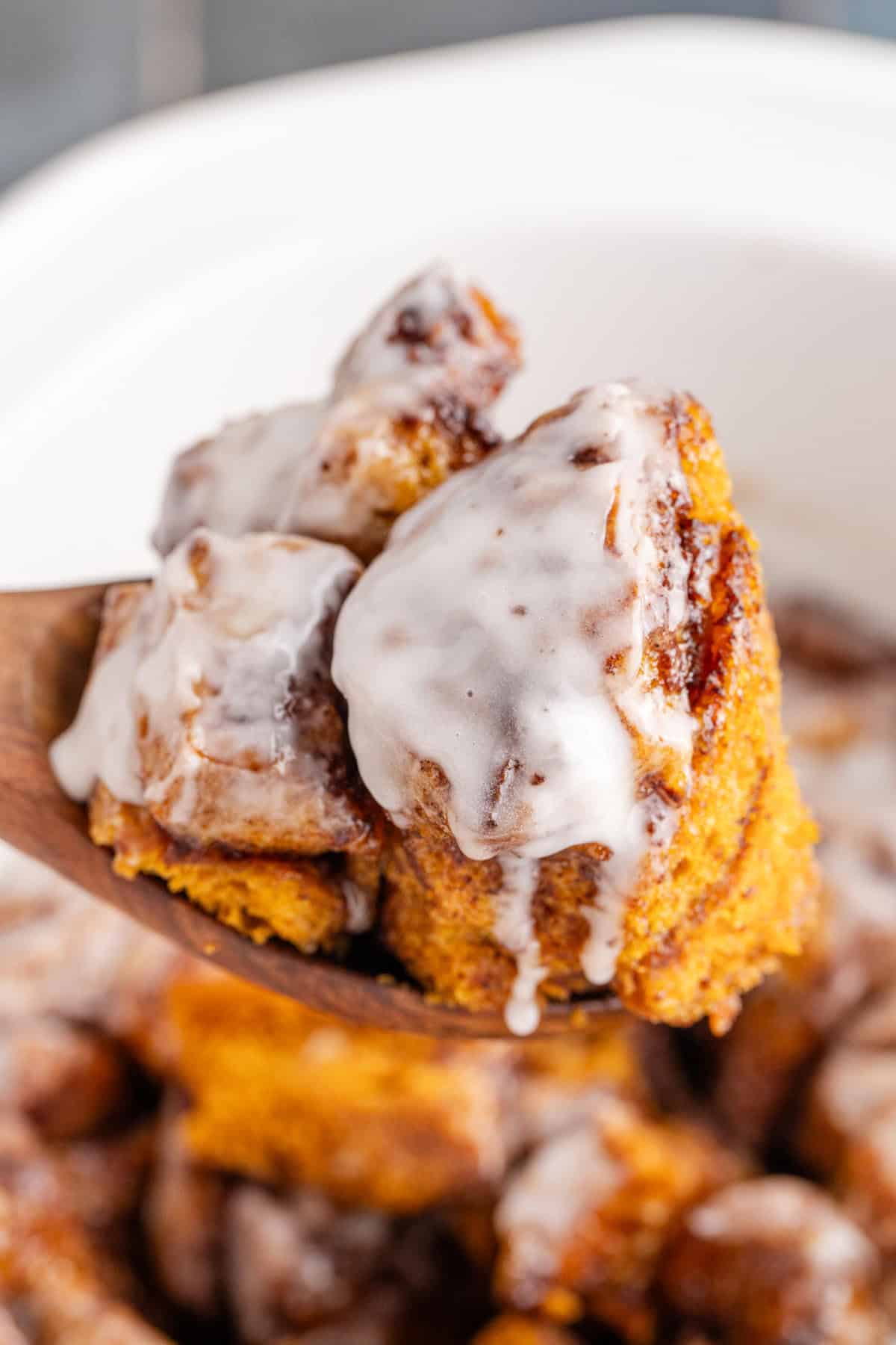 Crock Pot Cinnamon Bun Casserole Scooped from Crock Pot with Wooden Spoon