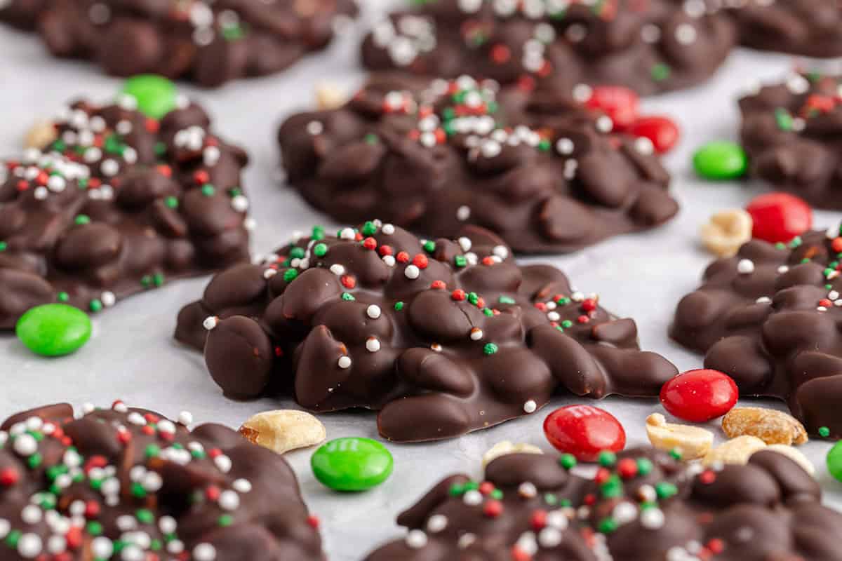 Crockpot Candy Chocolate Peanut Clusters with Sprinkles on Parchment Paper with M&Ms