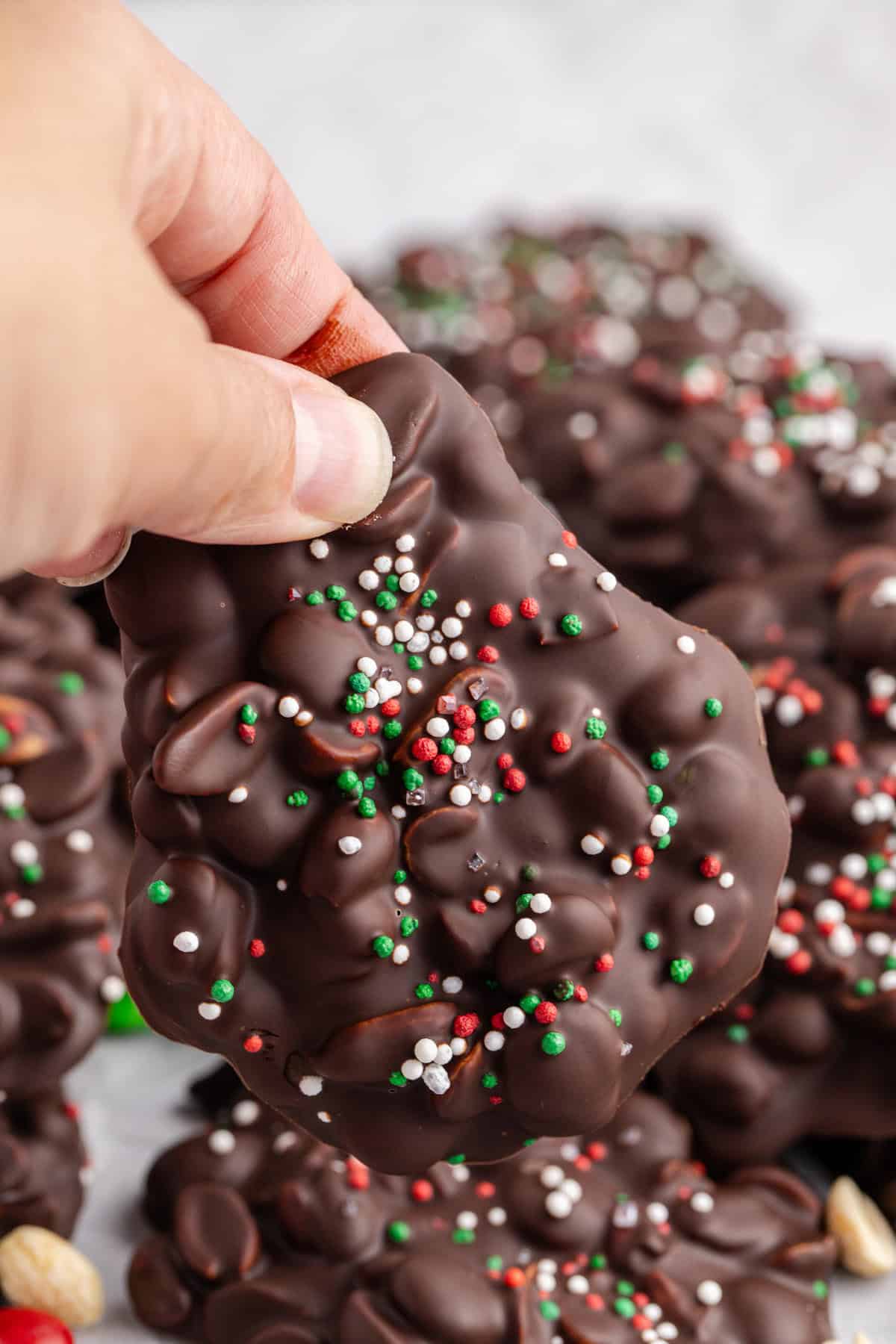 Crockpot Candy Dark Chocolate Peanut Clusters with Sprinkles Being Held Up