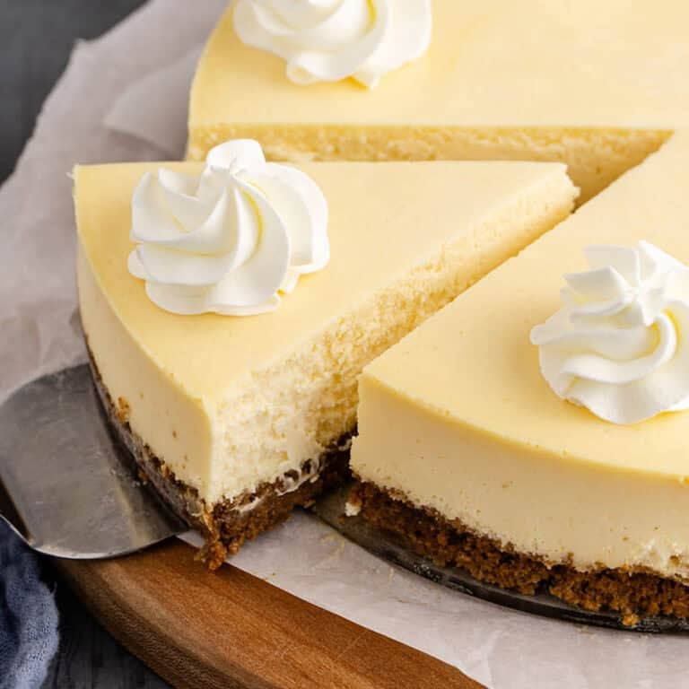 Eggnog Cheesecake Garnished with Whipped Cream and Sliced on Cake Server
