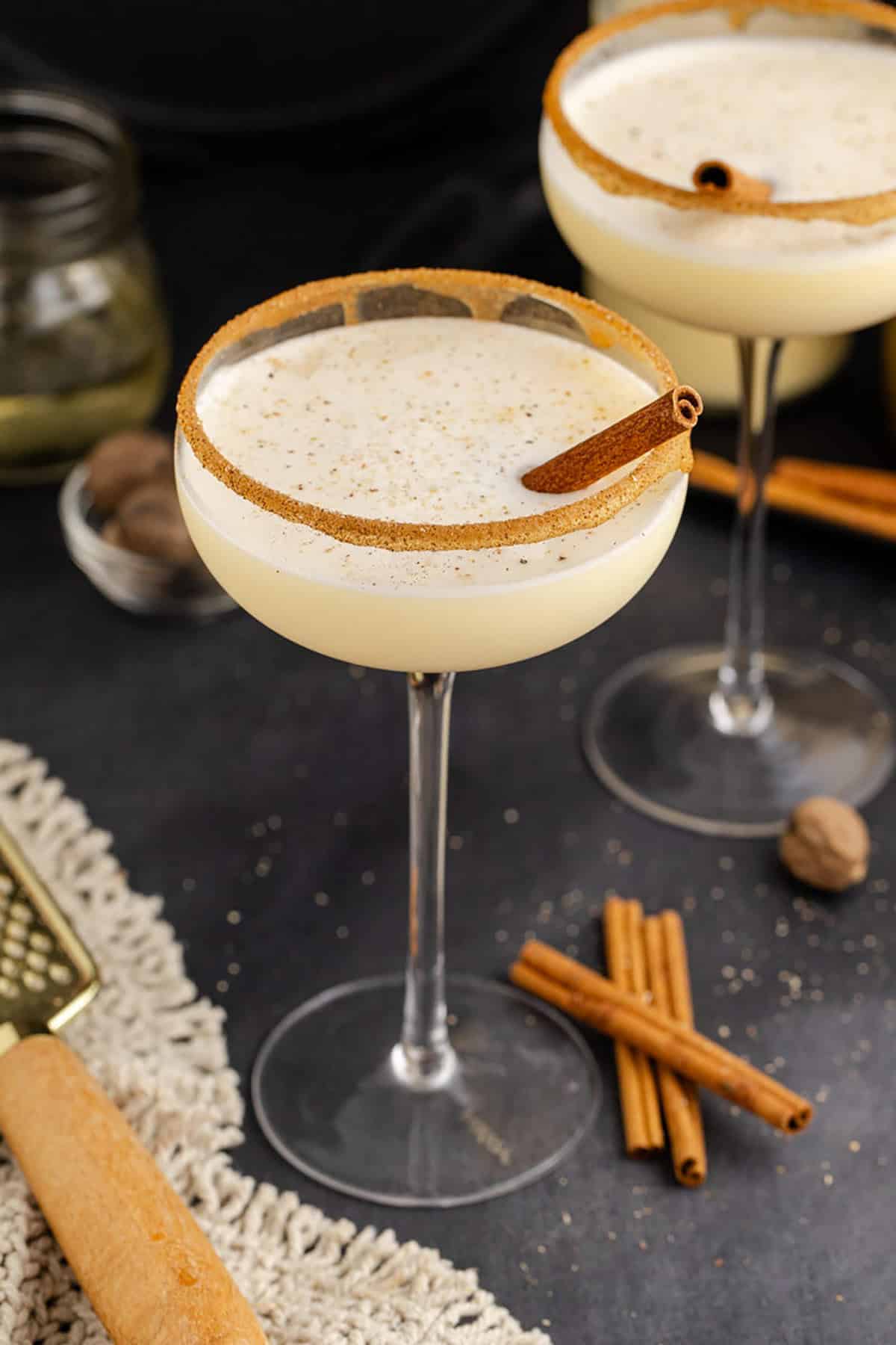 Eggnog Martini Cocktails Garnished with Cinnamon Sticks and Cinnamon Sugar Rim