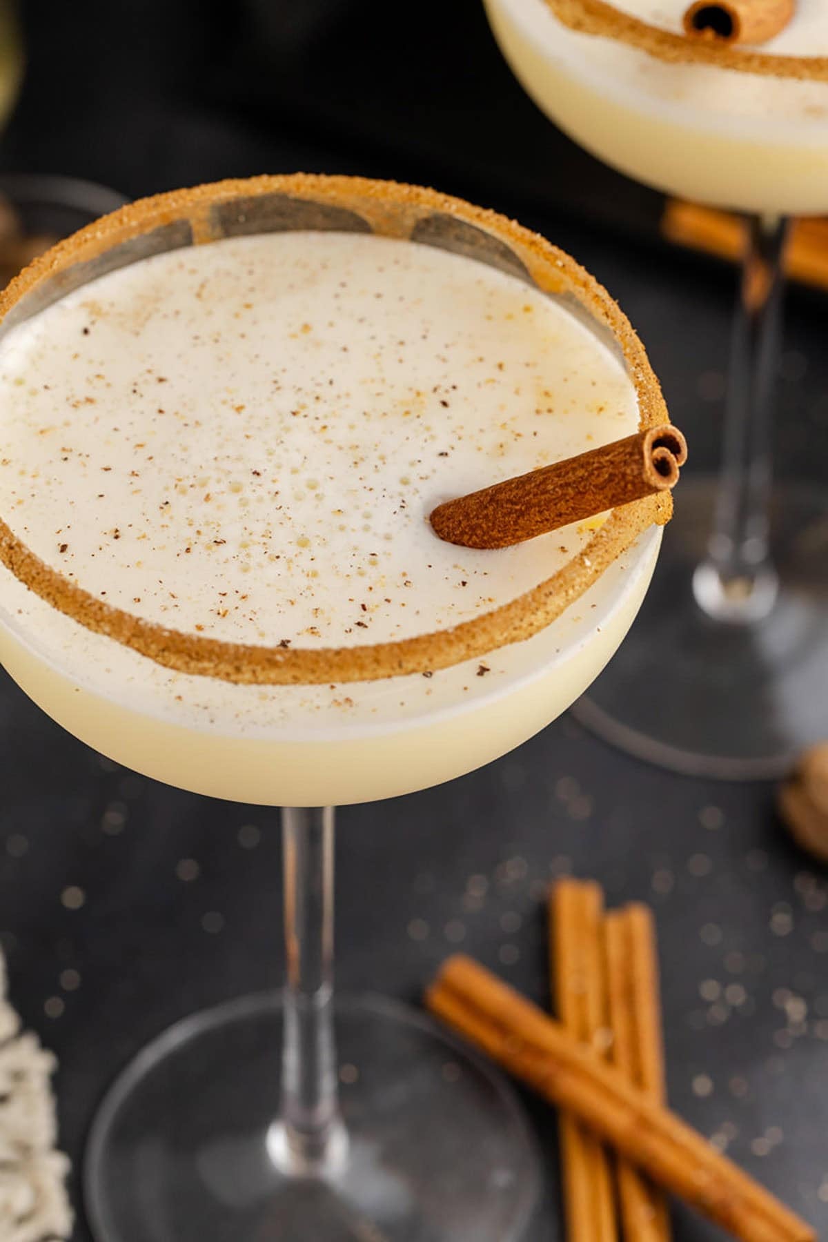 Eggnog Martini Cocktails Garnished with Cinnamon Sticks and Cinnamon Sugar Rim
