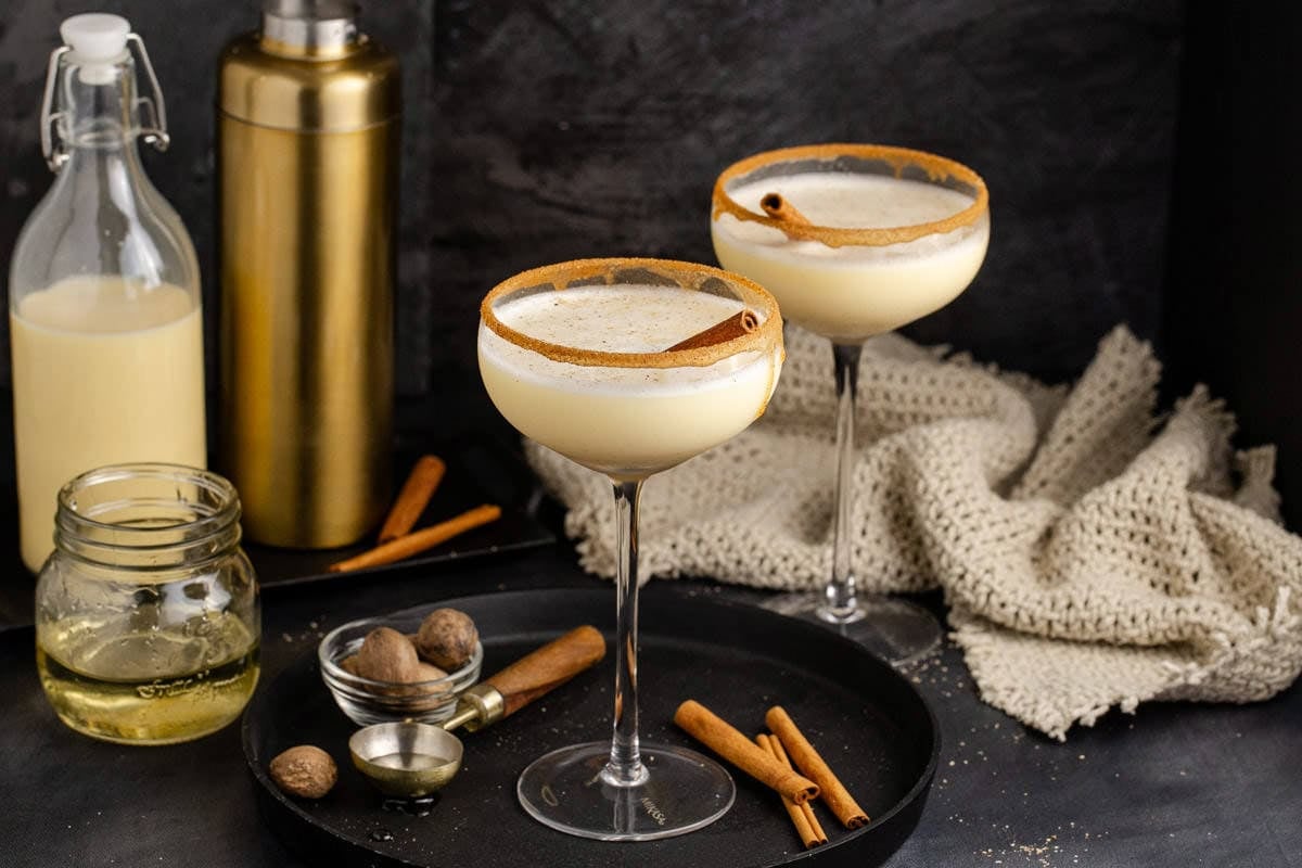 Eggnog Martini Cocktails Garnished with Cinnamon Sticks and Cinnamon Sugar Rim