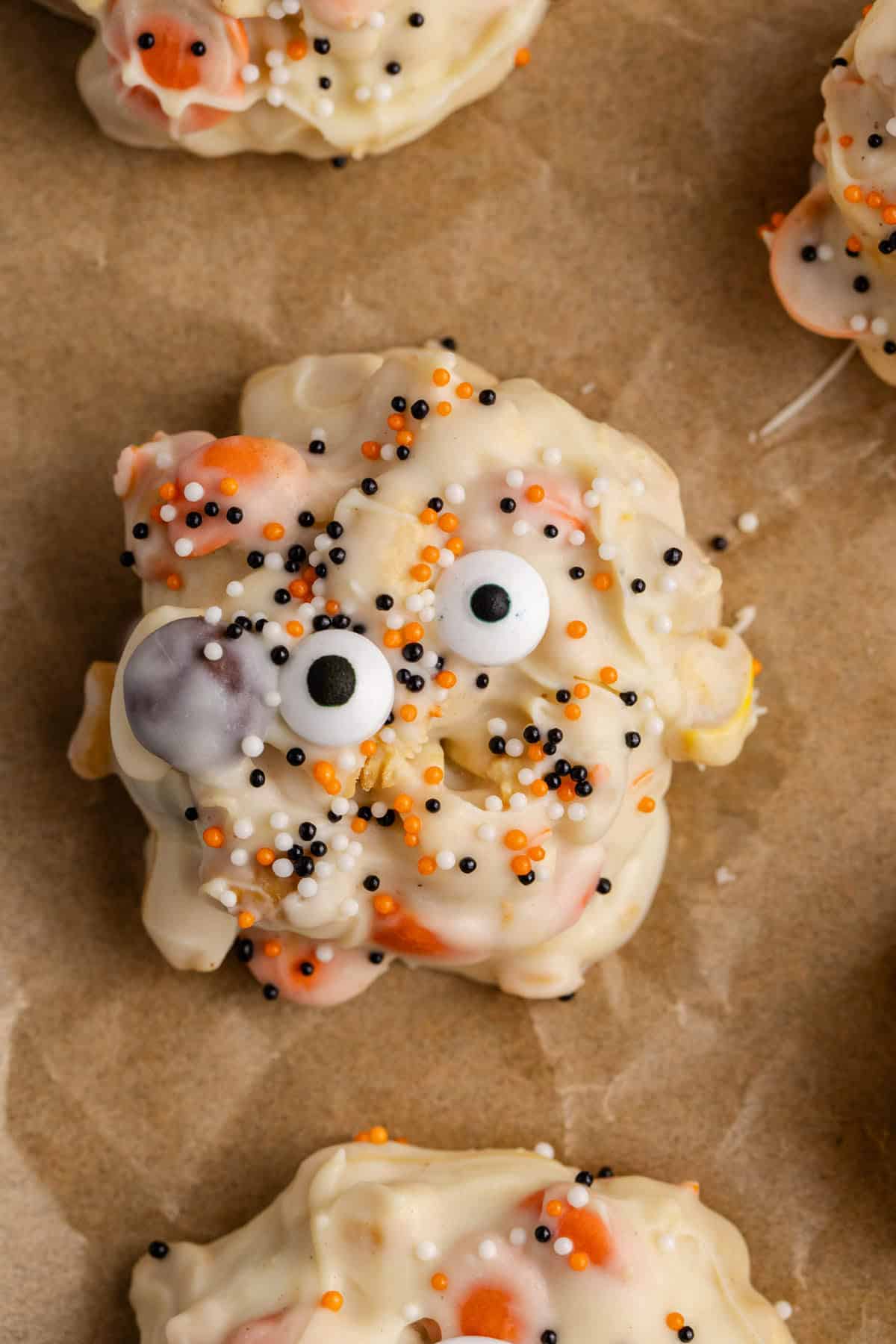 White Chocolate Peanut Halloween Crockpot Candy with Halloween Sprinkles and Edible Eyeballs on Parchment Sheet