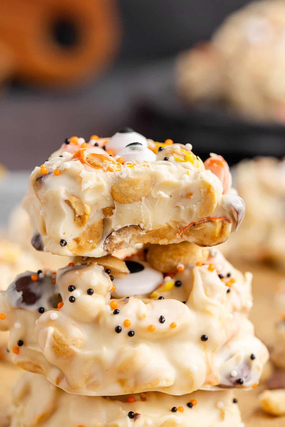 White Chocolate Peanut Halloween Crockpot Candy with Halloween Sprinkles and Edible Eyeballs Stacked with Bite Showing Inside