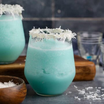 Jack Frost Cocktail in a Clear Glass Garnished with Shredded Coconut Rim
