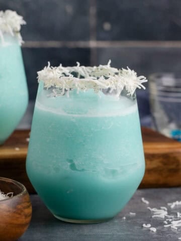 Jack Frost Cocktail in a Clear Glass Garnished with Shredded Coconut Rim