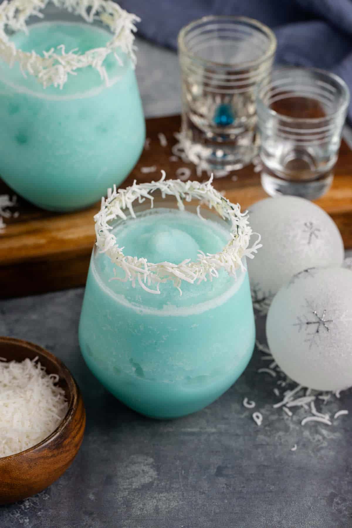 Blue Jack Frost Cocktail in a Clear Glass Garnished with Shredded Coconut Rim