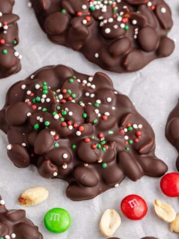 Crockpot Candy Chocolate Peanut Clusters with Sprinkles on Parchment Paper