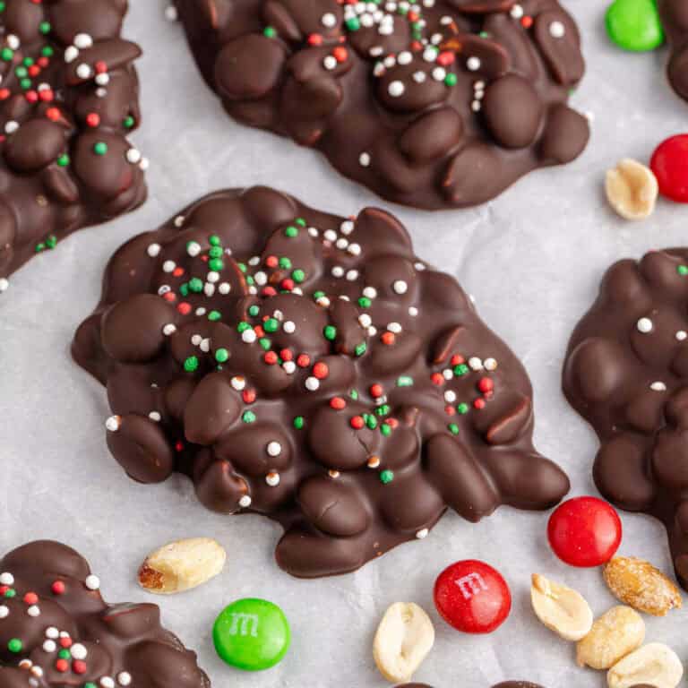 Crockpot Candy Chocolate Peanut Clusters with Sprinkles on Parchment Paper