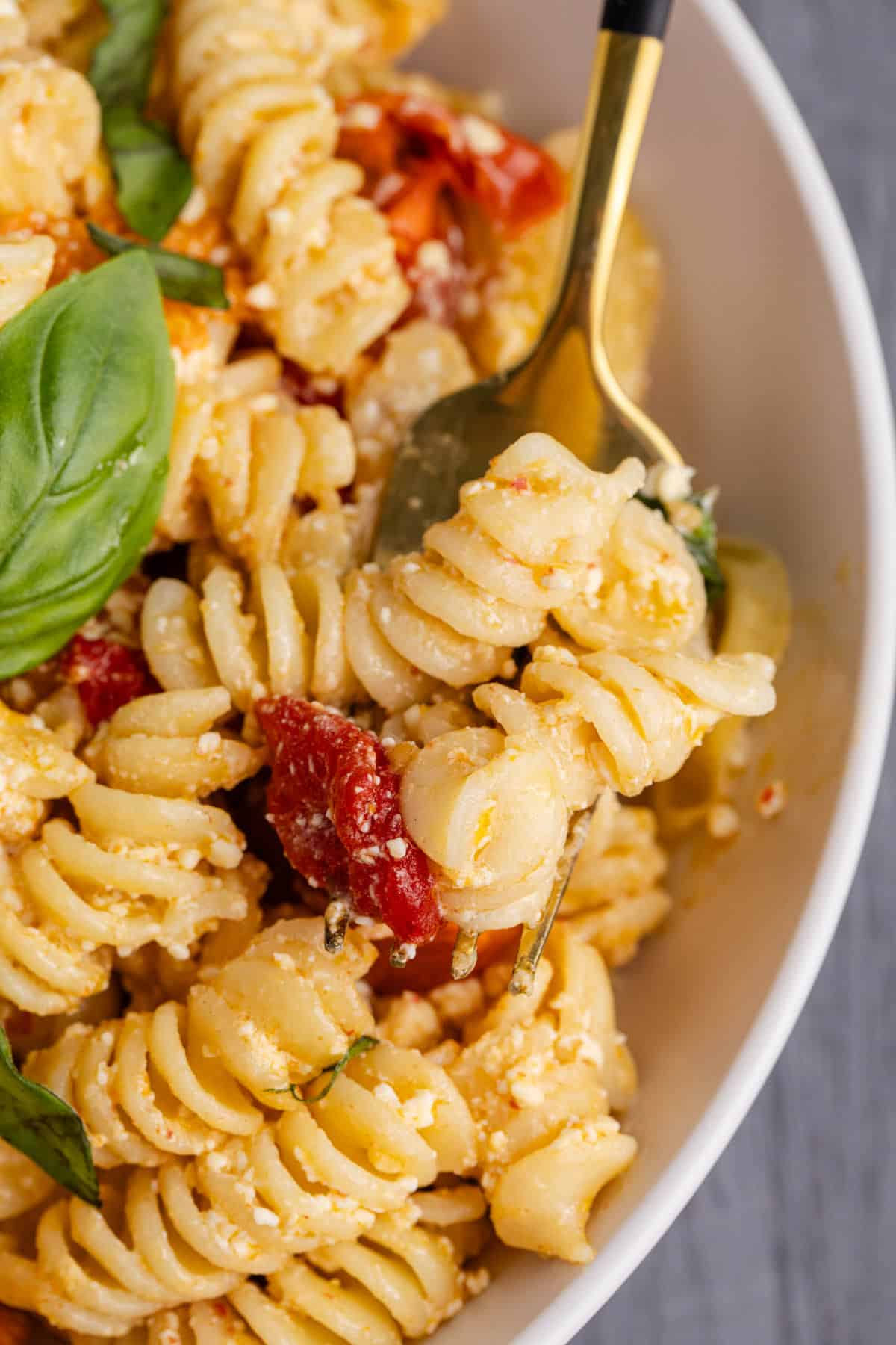 Feta Pasta Recipe in a Bowl Served with Fresh Basil on a Fork Close Up