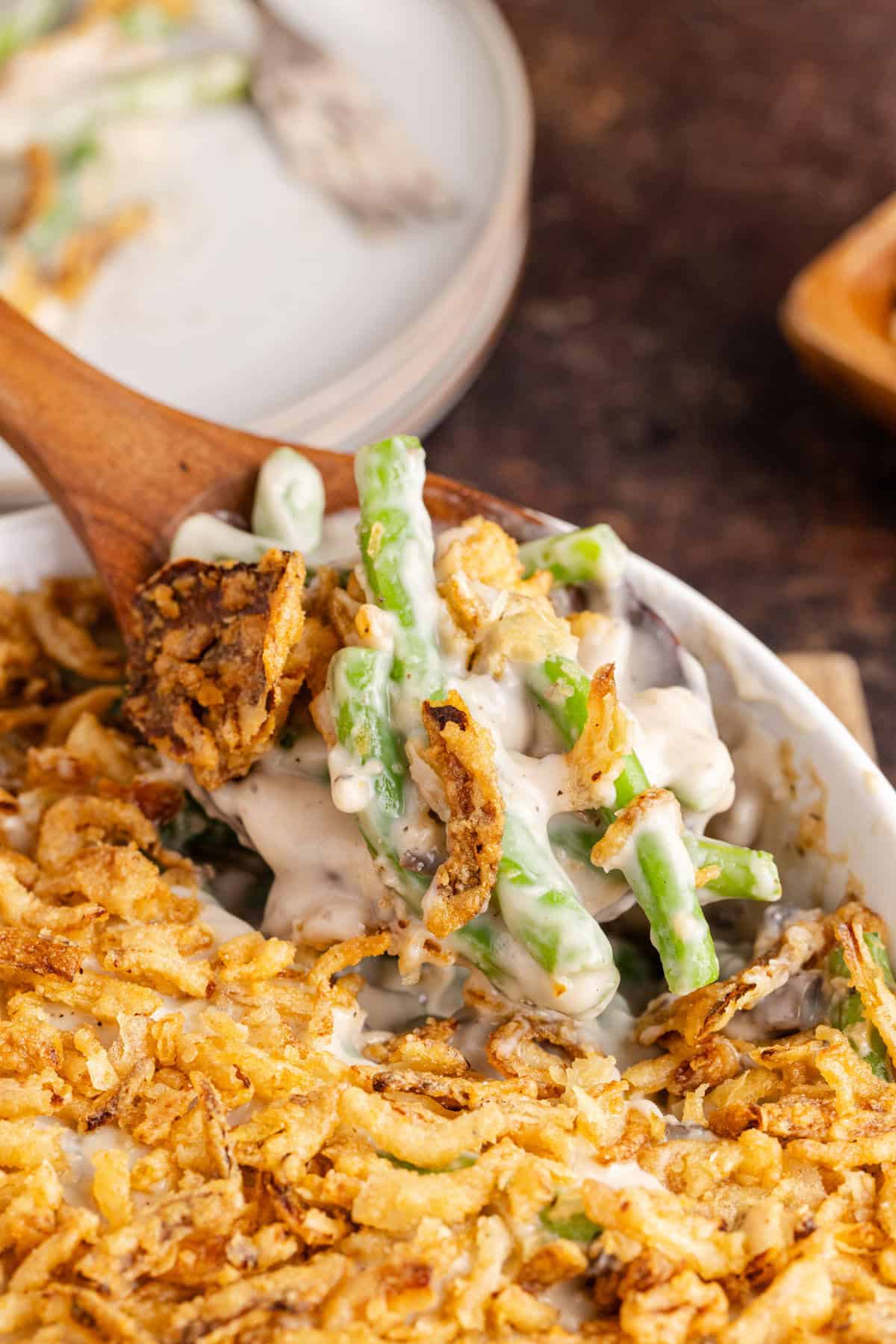 Green Bean Casserole being scooped on a wooden spoon
