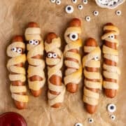 Hot Dog Mummies on a baking sheet with candy eyeballs