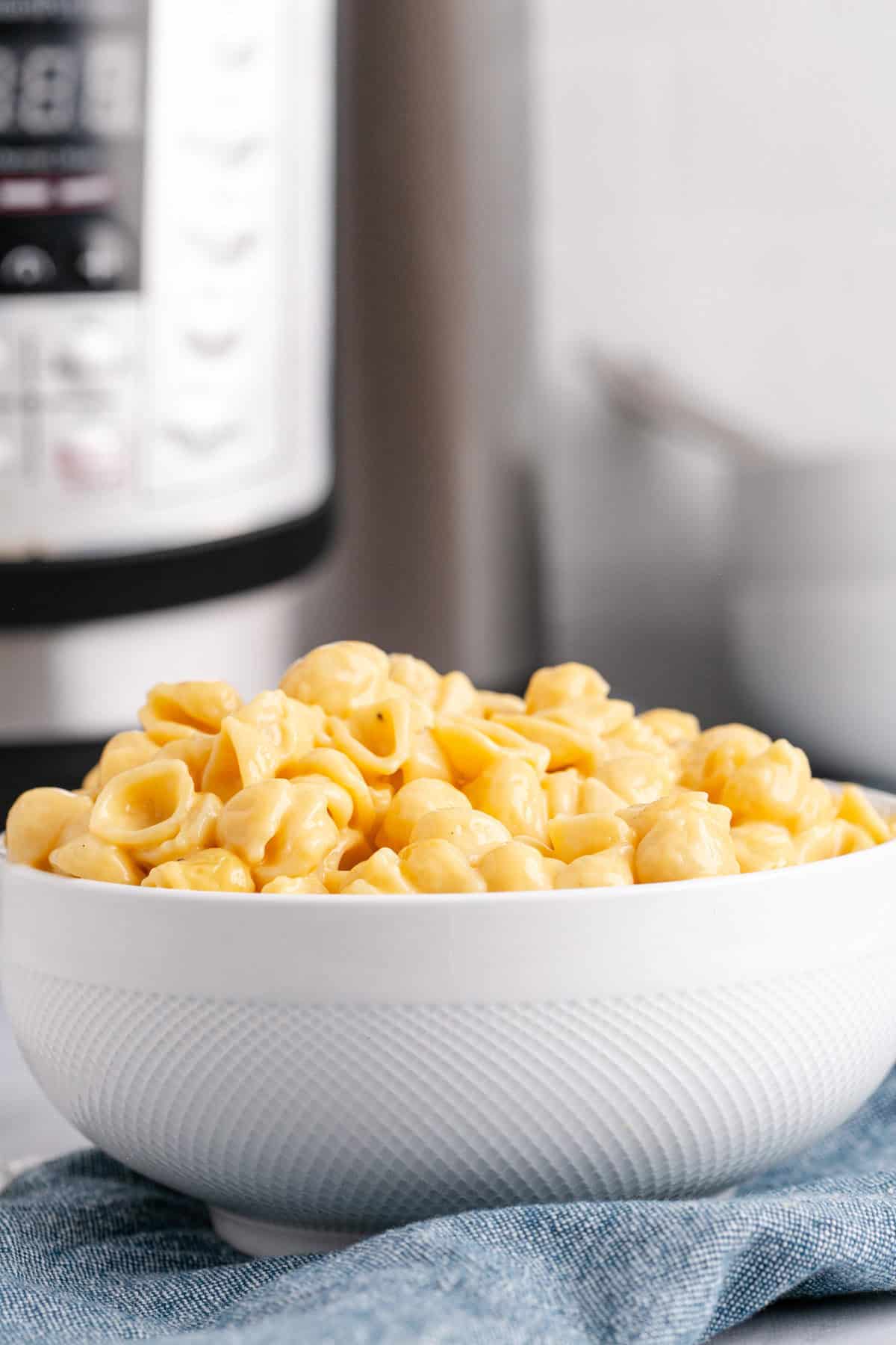 Instant Pot Mac and Cheese Velveeta Mini Shells Served in a Bowl with Instant Pot in Background