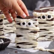 Mummy Brownies standing upright on a counter about to be picked up