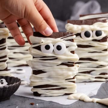 Mummy Brownies standing upright on a counter about to be picked up