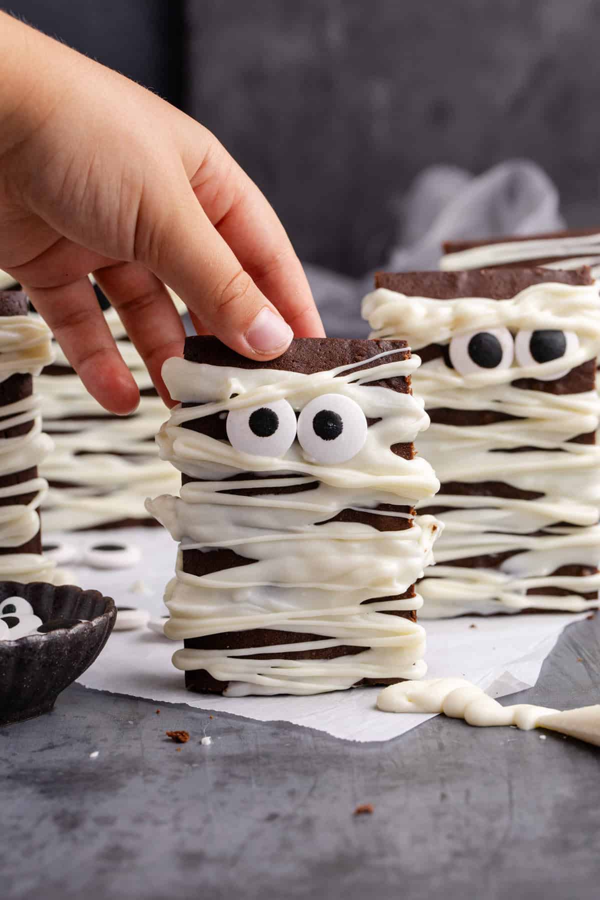 Mummy Brownies standing upright on a counter about to be picked up