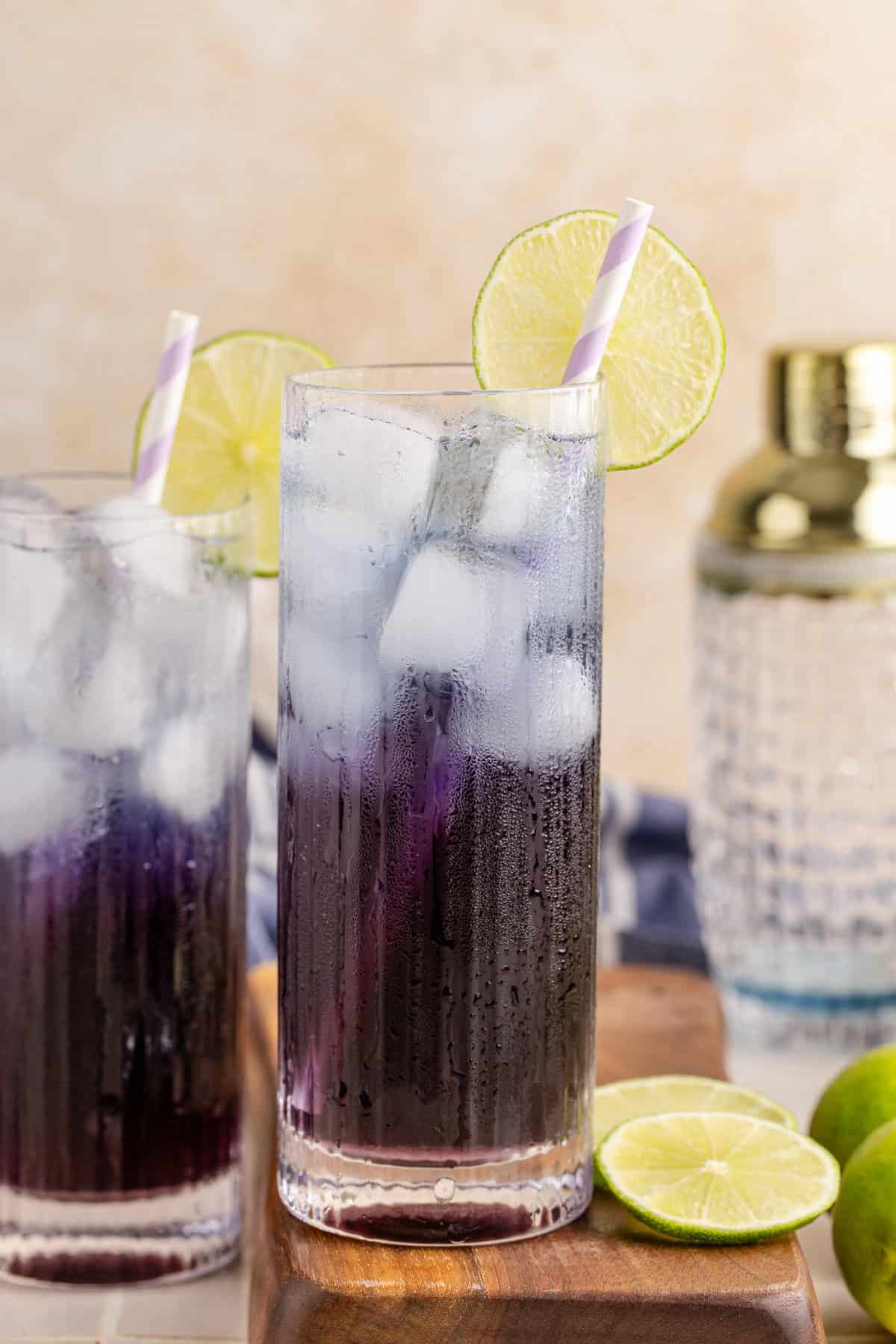 Purple Rain Cocktail on a cutting board with lime slices beside