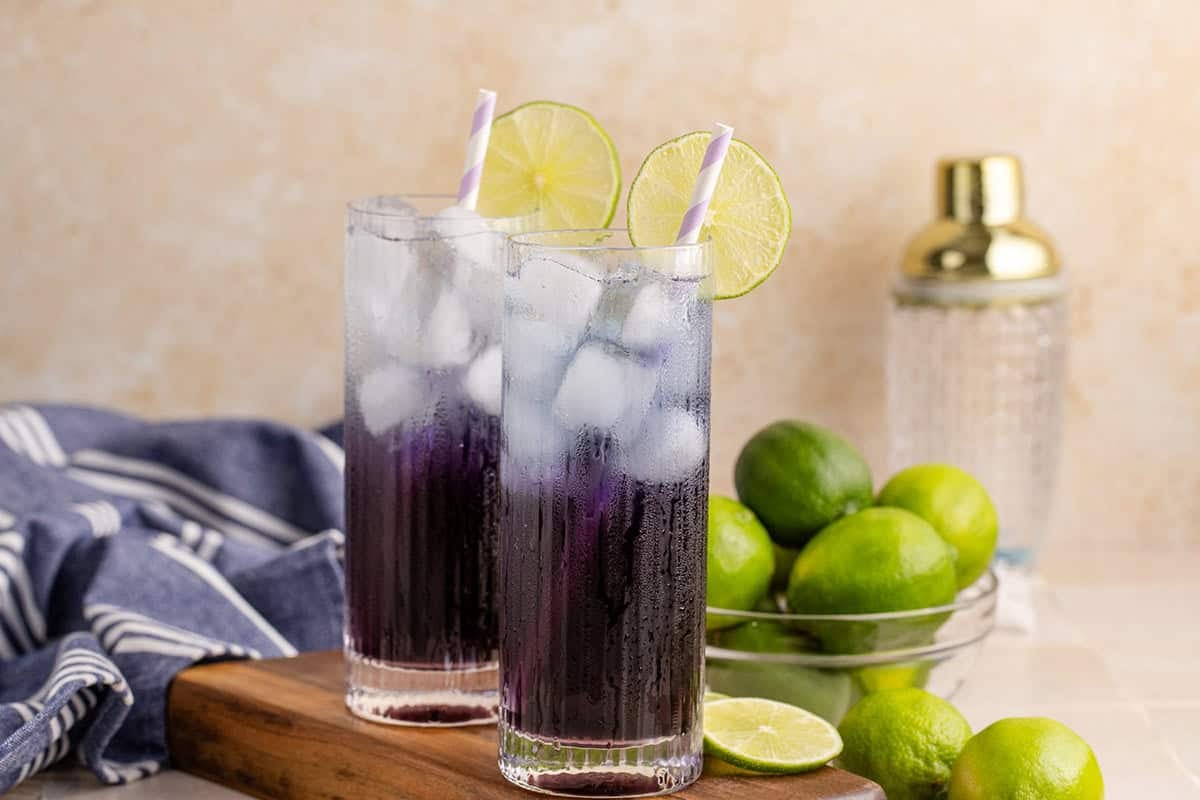 Purple Rain Cocktail on a cutting board with limes in the background