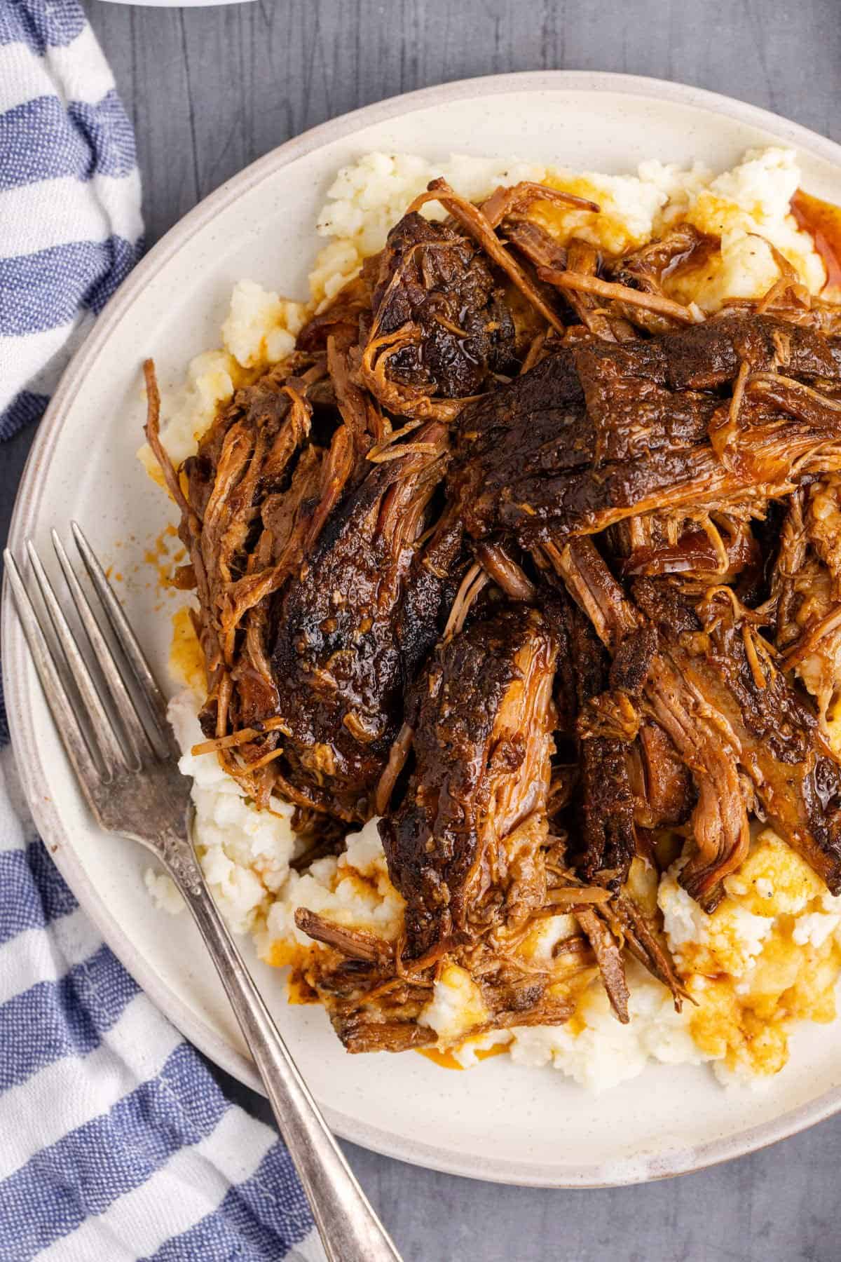 Slow Cooker Brisket close up on a plate with mashed potatoes and a fork