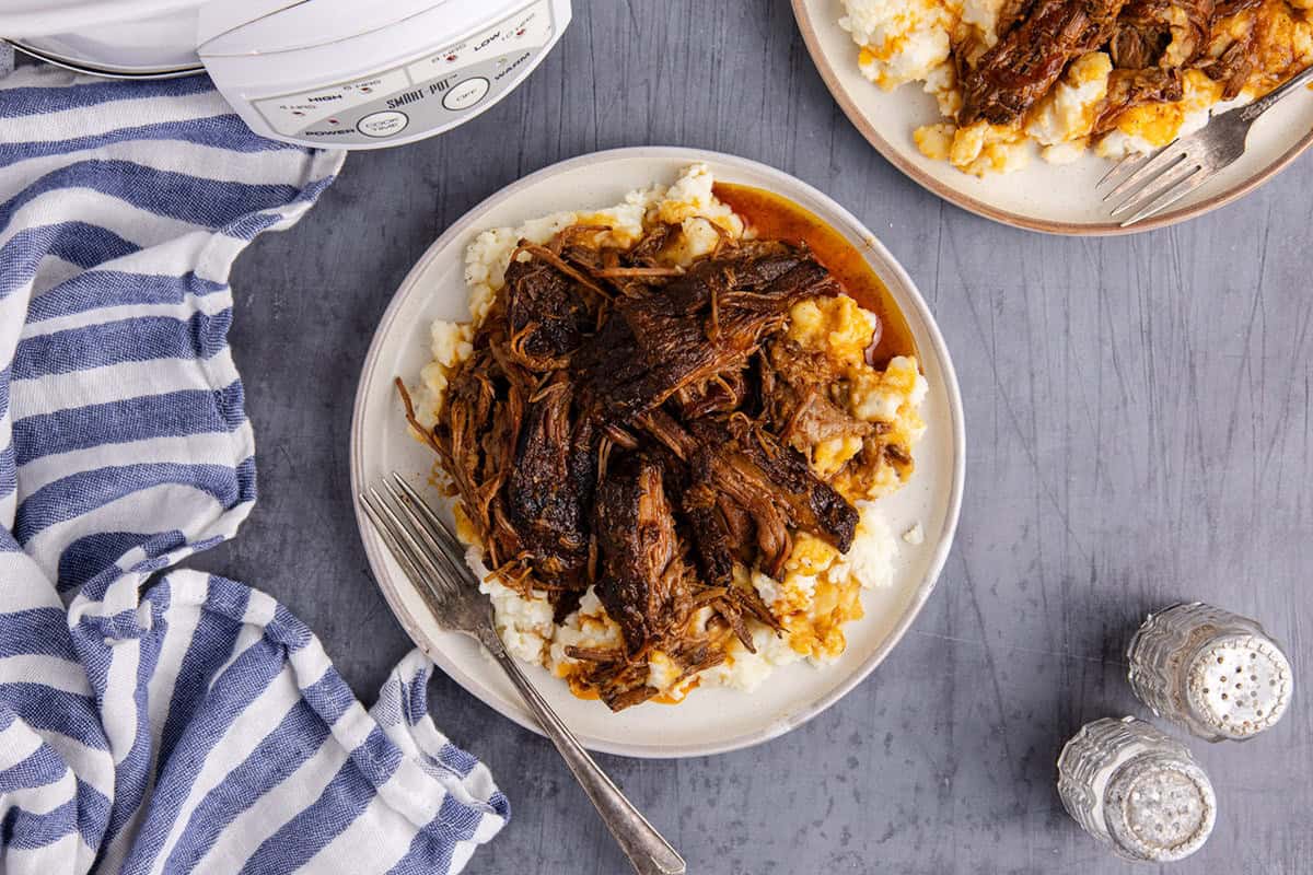 Slow Cooker Brisket shredded on a plate with mashed potatoes from above