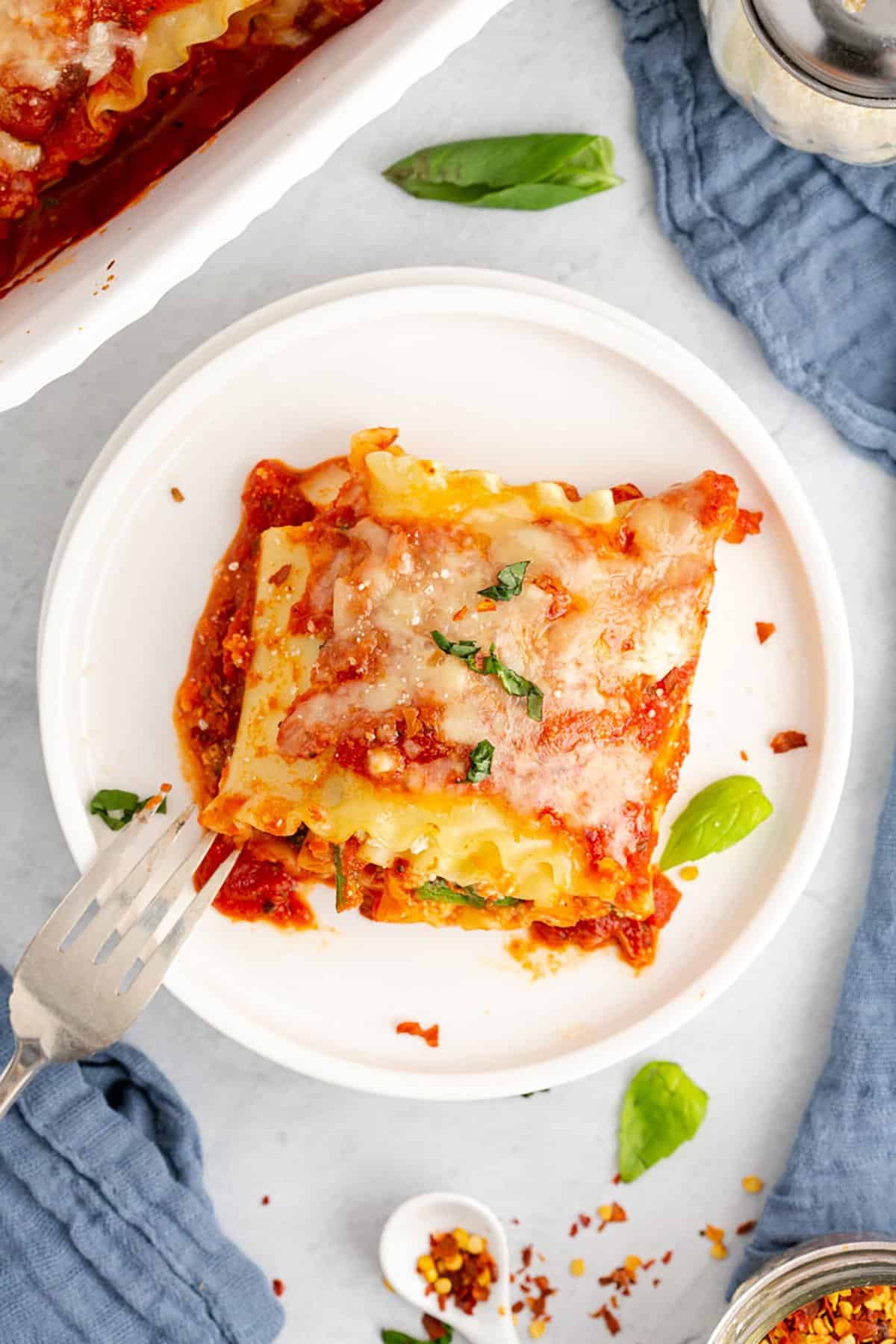 Spinach Lasagna Roll Ups Served on a Plate and Garnished with Fresh Basil