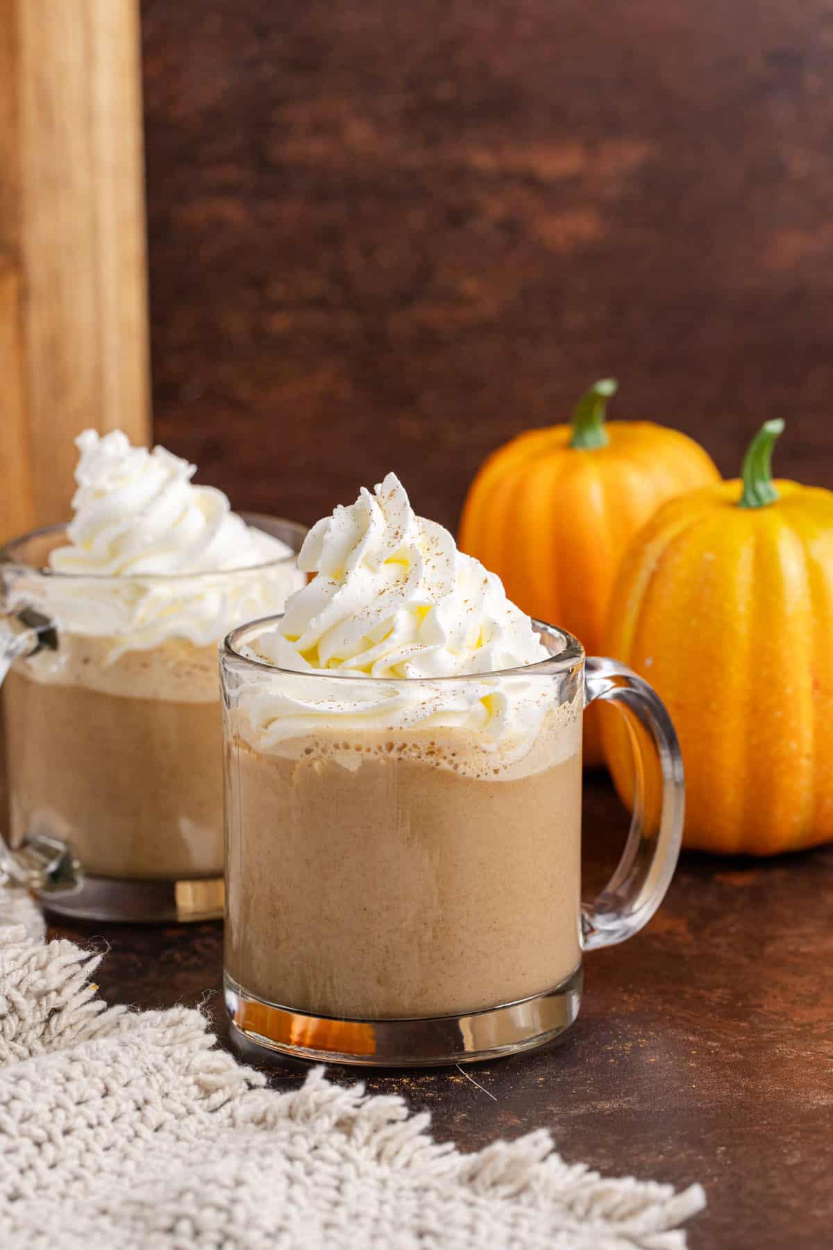 Starbucks Pumpkin Spice Latte on a cutting board with pumpkins in the back