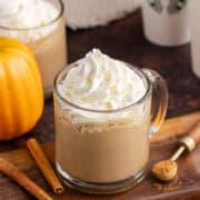 Starbucks Pumpkin Spice Latte on a cutting board with takeaway cups in the back