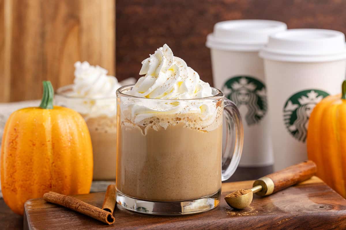 Starbucks Pumpkin Spice Latte in a Mug with whipped cream on a cutting board