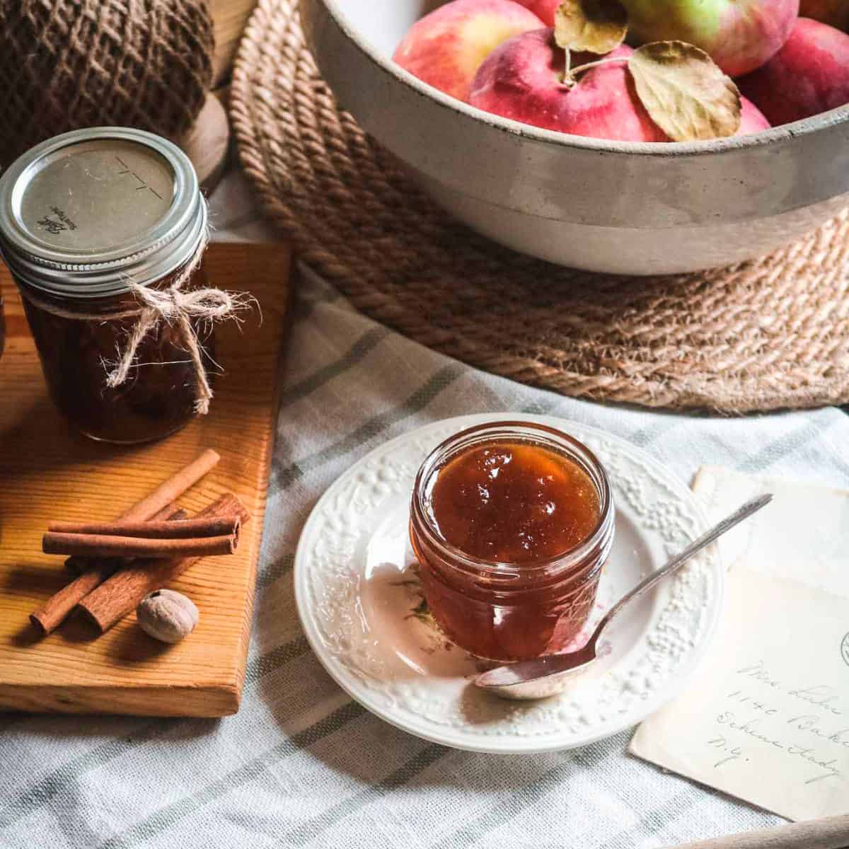Apple Jam in a mason jar on a plate with a spoon beside it