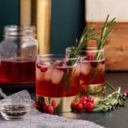 Cranberry Shrub cocktails in glasses with the shrub in a mason jar in the back